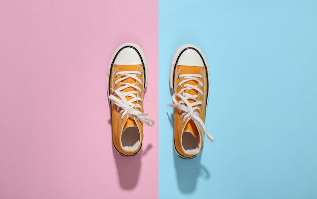 Yellow high-top sneakers (gumshoes) on pink blue bright background. Top view. Minimalism