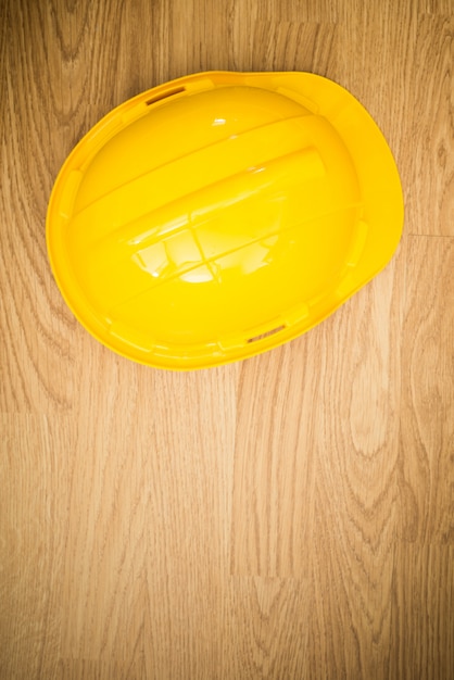 Yellow industrial protective helmet on wooden