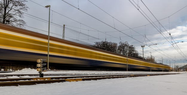 A yellow intercity electric train passes a station near the city Long exposure to the train