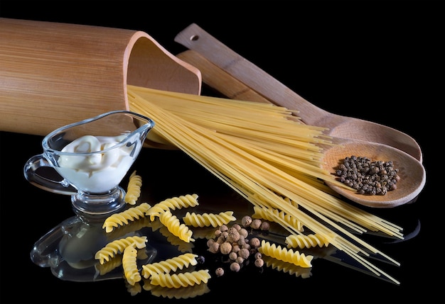 Yellow italian pasta, spaghetti, black pepper on black background