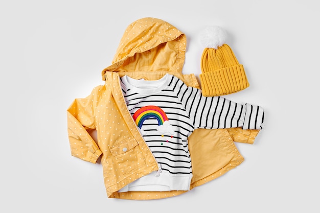 Yellow jacket and striped jumper on white background. Set of children's clothes for autumn. Fashion kids outfit.