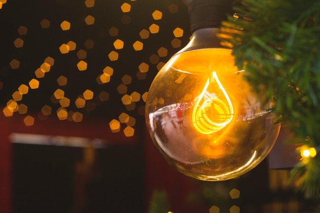 Yellow lamp among Christmas tree branches and Christmas lights.