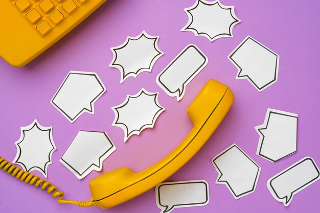 Photo yellow landline phone with speech bubble on purple surface