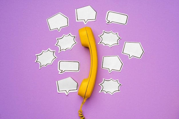 Photo yellow landline phone with speech bubble on purple