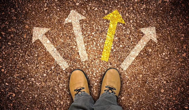 Photo yellow leather shoes and four chalky arrows on ground choice concept