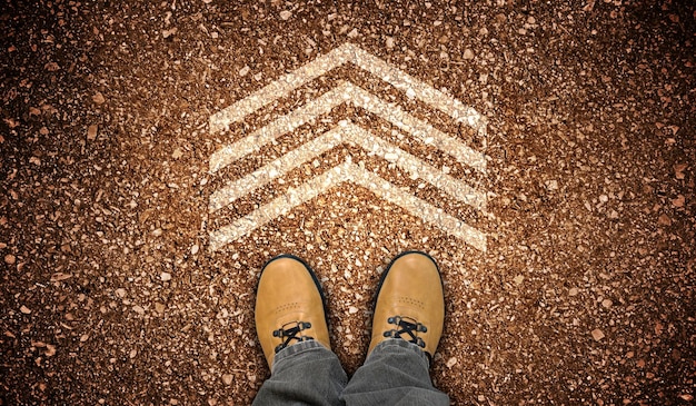 Yellow leather shoes and one geometrical chalky arrow on ground destination concept