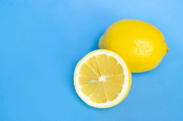 レモンの半分と黄色のレモンは青い背景のクローズアップにあります