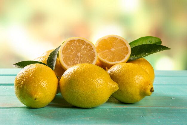 Yellow lemons on green wooden background