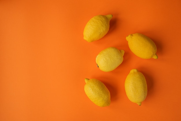 Foto limoni gialli su uno sfondo arancione. vista dall'alto