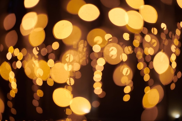 Le luci gialle del bokeh dalle ghirlande di festa di natale hanno offuscato le luci dell'estratto del fondo festivo