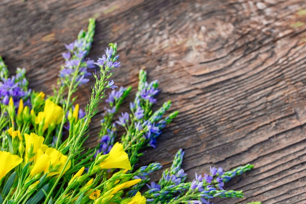 Yellow and lilac flowers lie on wooden background, copy space, beautiful postcard background