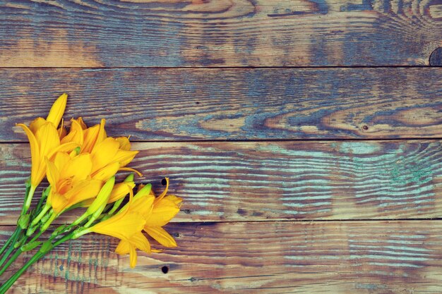 Yellow lily flowers on a wooden background