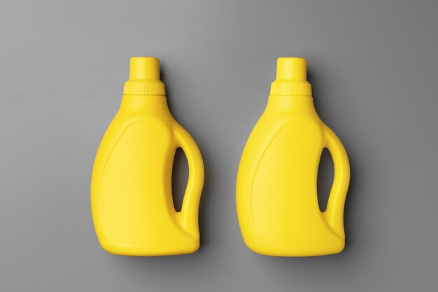 Photo yellow liquid detergents containers on gray background top view