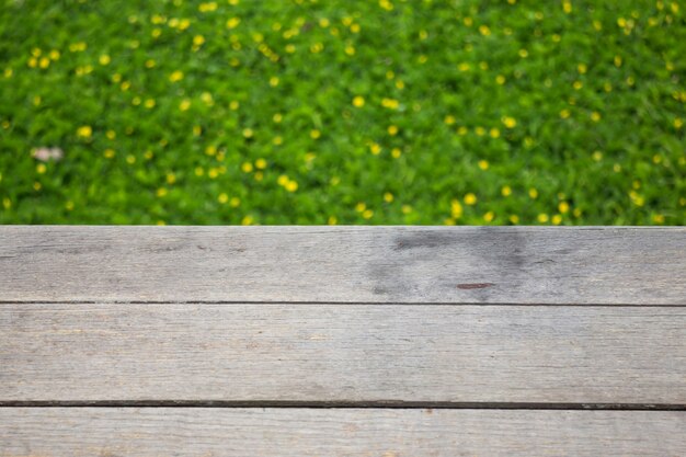 Yellow little flower on green grass with wooden background