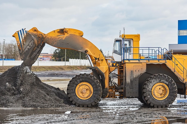 A yellow loader pours a pile of rubble and dirty earth for loading into construction equipment