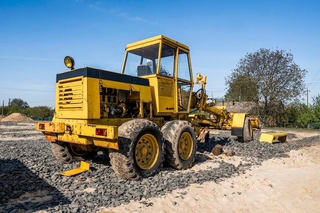 Yellow loader with empty bucket stands on a stone gravel during road construction works