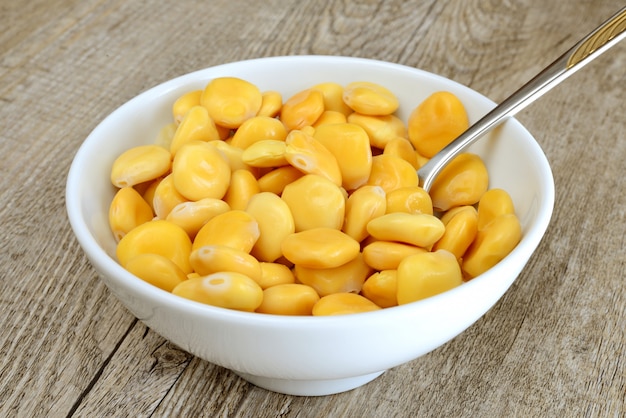 Yellow lupins on wooden table in white bowl