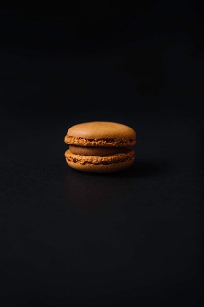 Yellow macaron and lemon flavor on black background