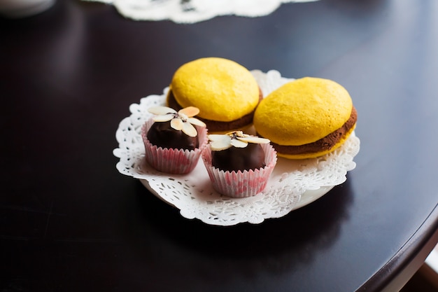 黄色のマカロンとチョコレートのお菓子が白い皿の上にあります。