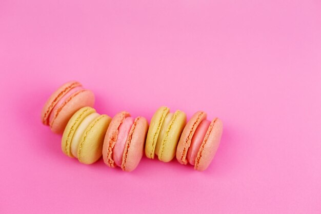 yellow macaroons on a pink background with a place for writing and cutting Minimalism