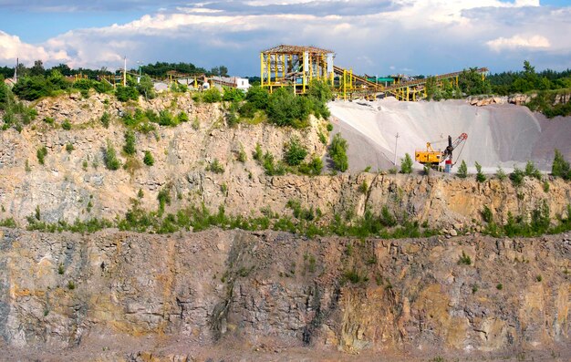 Yellow machine stonecutter stands with plenty of macadam in a quarry