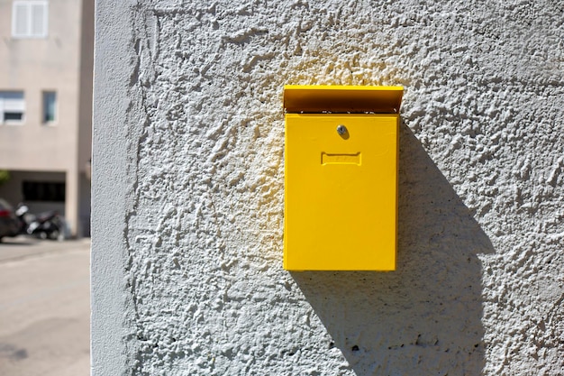 Cassetta postale gialla sul muro al giorno di sole casella per lettere e corrispondenza