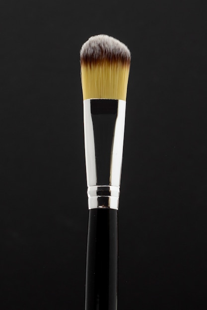 Yellow makeup brush with silver and black background