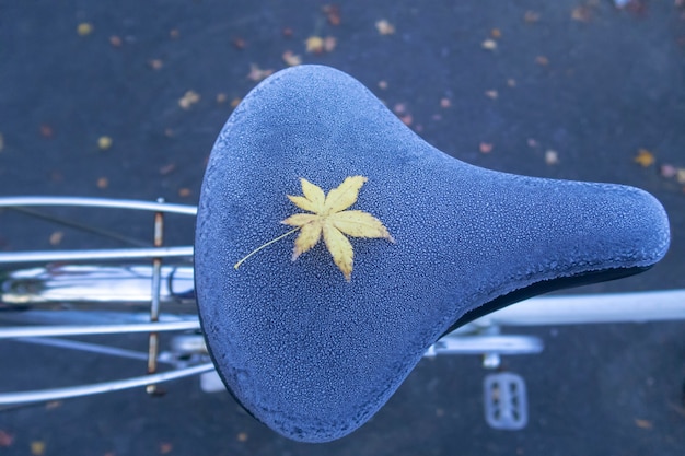 Photo a yellow maple leave on frozen bicycle seat during autumn in japan.