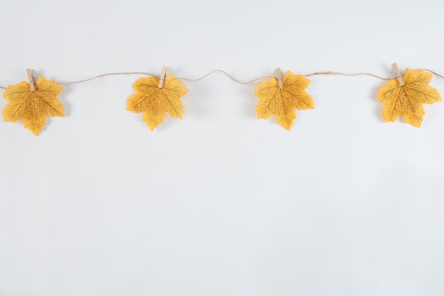 Yellow maple leaves and wooden clips on white table