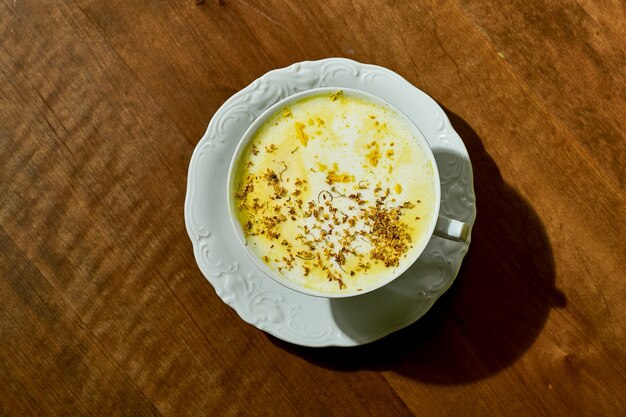 Matcha giallo in una tazza bianca su uno sfondo di legno. latte art alla partita