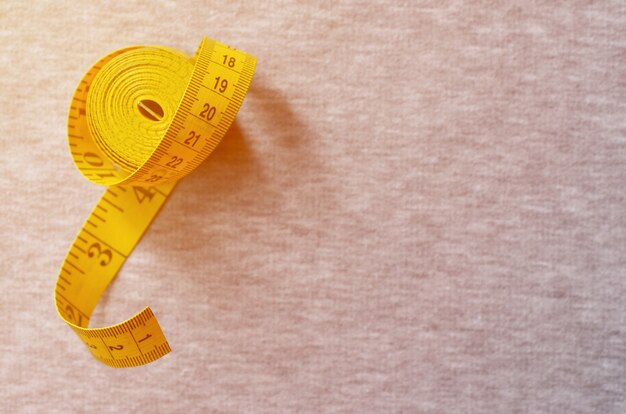 Yellow measuring tape lies on a gray knitted fabric