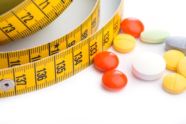 Yellow measuring tape and pills on a white table