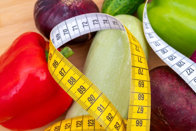 Yellow measuring tape and vegetables on a wooden cutting board. Healthy lifestyle diet.