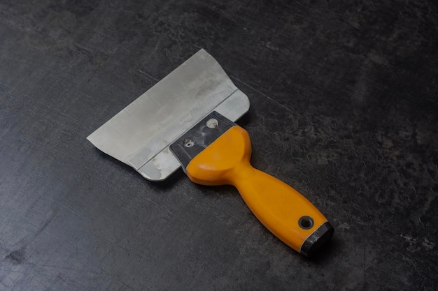 yellow metal trowel for plastering and cement work on a concrete table