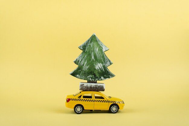 Yellow miniature taxi carrying a Christmas tree