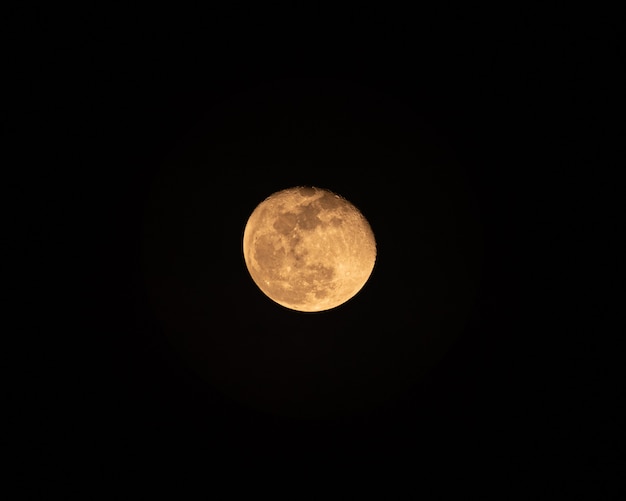 Yellow the Moon glowing with rugged texture in the night sky