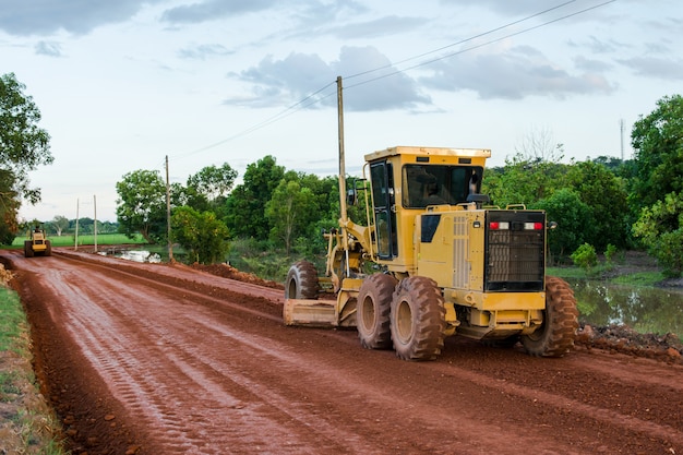 Photo yellow motor grader road working on road construction site of new road.