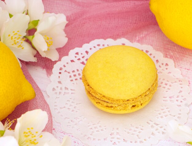 yellow multi layer cookies macaroon on a wooden stand with flowers