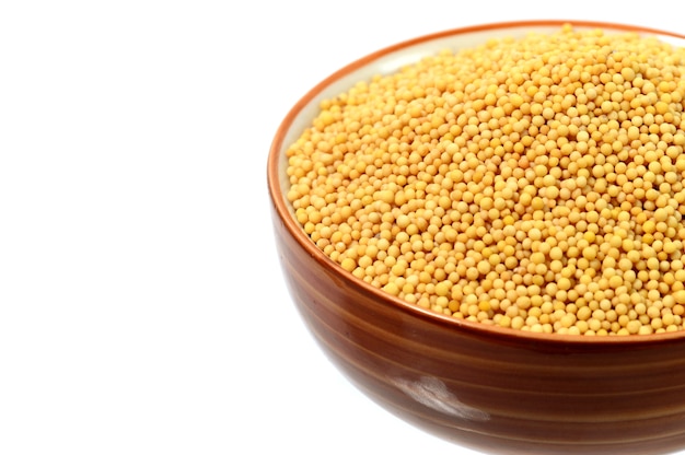 Yellow mustard seeds in bowl isolated on white background