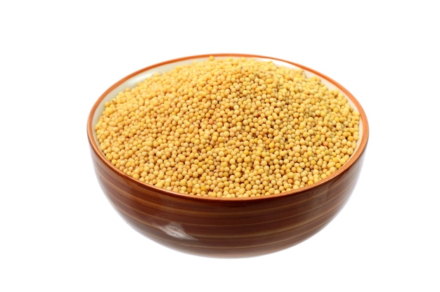 Yellow mustard seeds in bowl isolated on white background