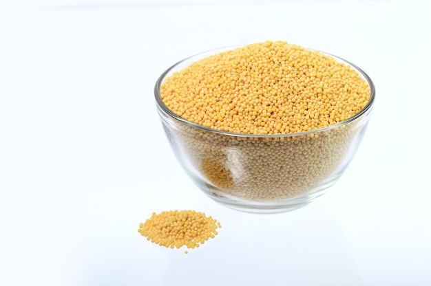 Yellow mustard seeds in glass bowl isolated