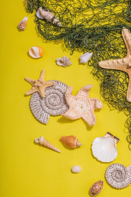 Yellow nautical background with sea shells starfishes and fishing net assorted marine animals vacation concept trendy hard light dark shadow flat lay top view