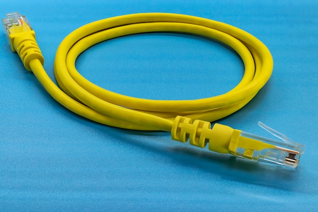 Желтый сетевой кабель с разъемами DOF. На синем фоне. Крупный план.