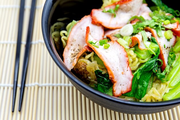 Yellow noodles served with sliced red pork