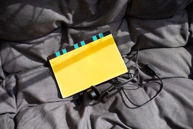 Yellow notebook and garniture on grey sofa in sunny day