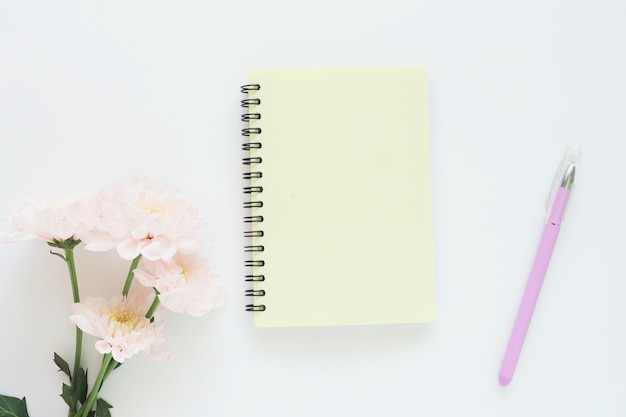 yellow notebook on a spring, gently pink chrysanthemums and a lilac pen