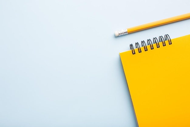 Yellow notebook with a pencil on a blue background space for your text