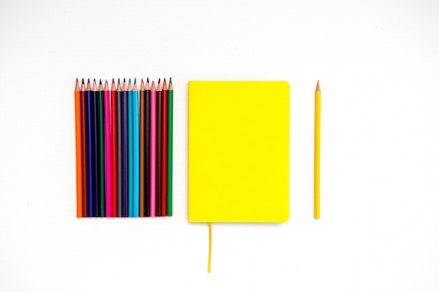 yellow Notepad with colored pencils on a white background