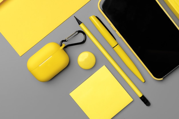 Yellow notepad with smartphone and pen on gray background close up