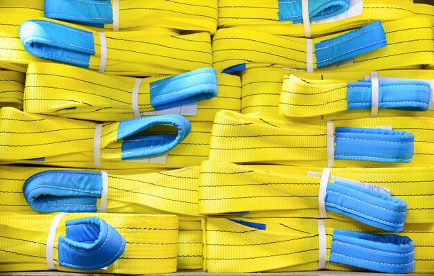 Yellow nylon soft lifting slings stacked in piles.